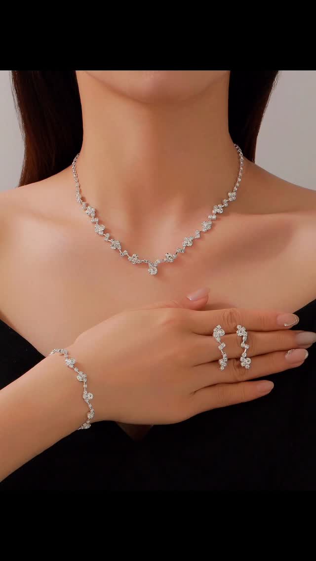 Silver jewelry set including necklace, bracelet, and ring on a model against a neutral background